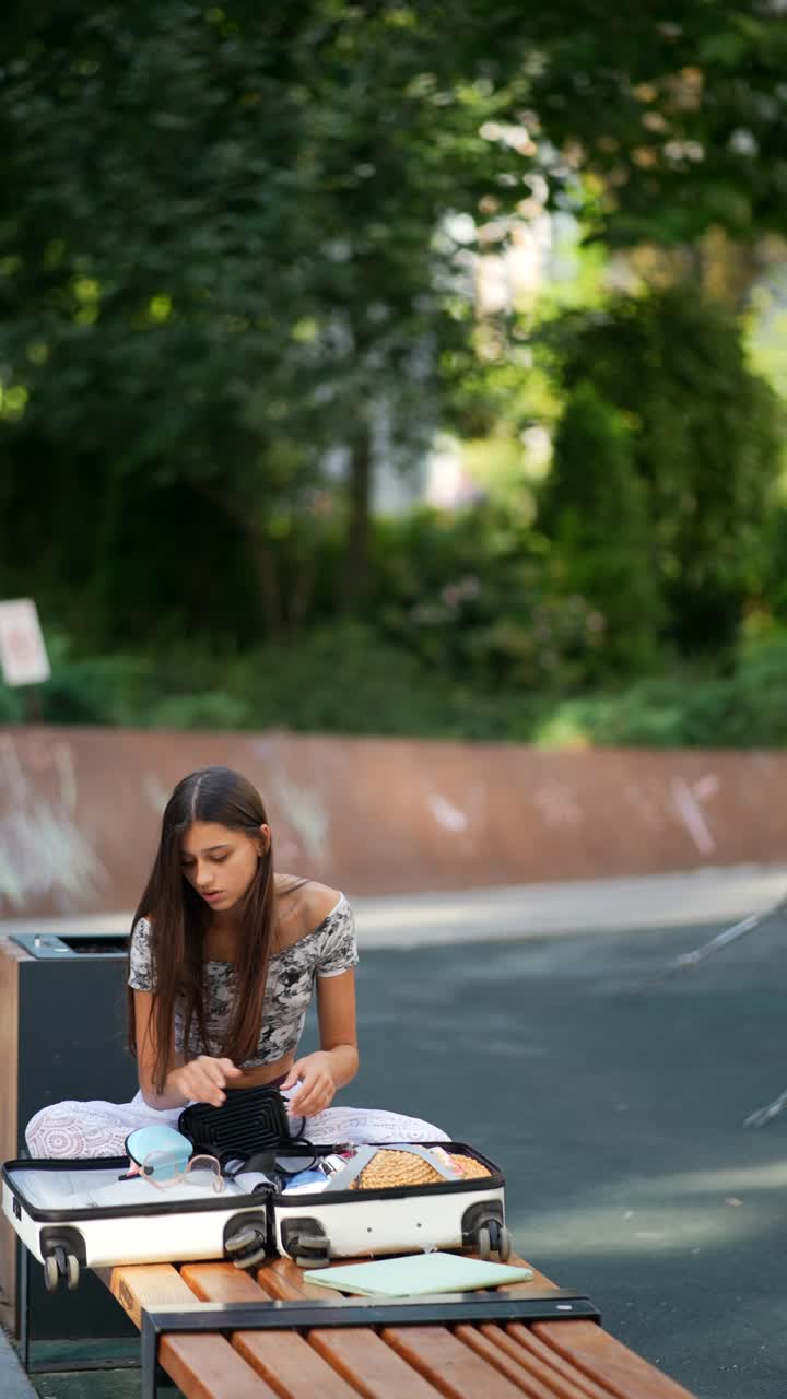 una mujer joven empacando una maleta en un parque.