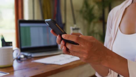 sección media de mujeres que usan teléfonos inteligentes mientras trabajan desde casa