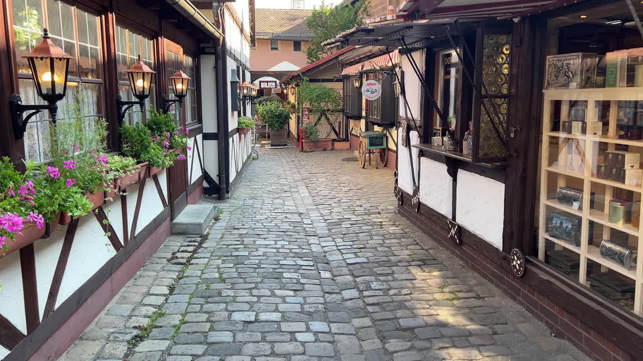 Tranquillo vicolo storico del mercato nella città vecchia di Norimberga con case a graticcio, piccoli negozi e strada acciottolata, che mostra l'autentica atmosfera della città bavarese
