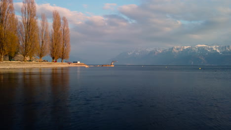 drone's flight over te leman lake from lutry, featuring the beach and the jetty, aiming towards french mountains