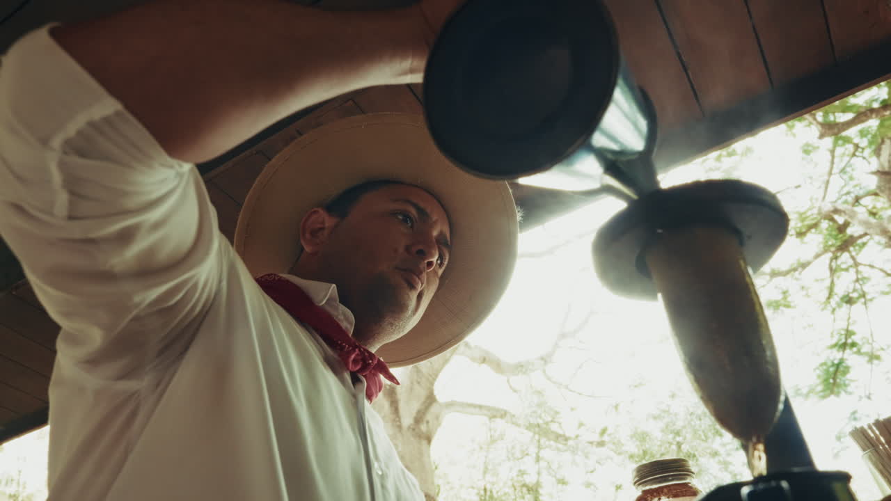 Close up shot of Costa Rican man with a hat pouring freshly brewed coffee.