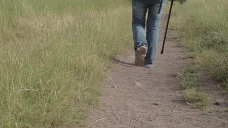 Hiker-on-dusty-countryside-path-with-walking-stick