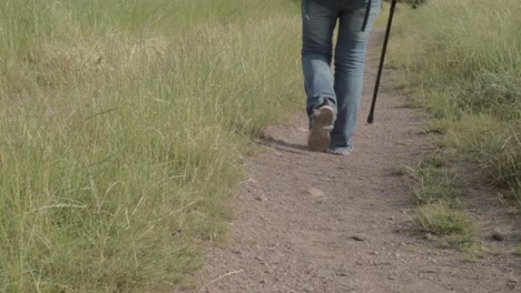 hiker on dusty countryside path with walking stick