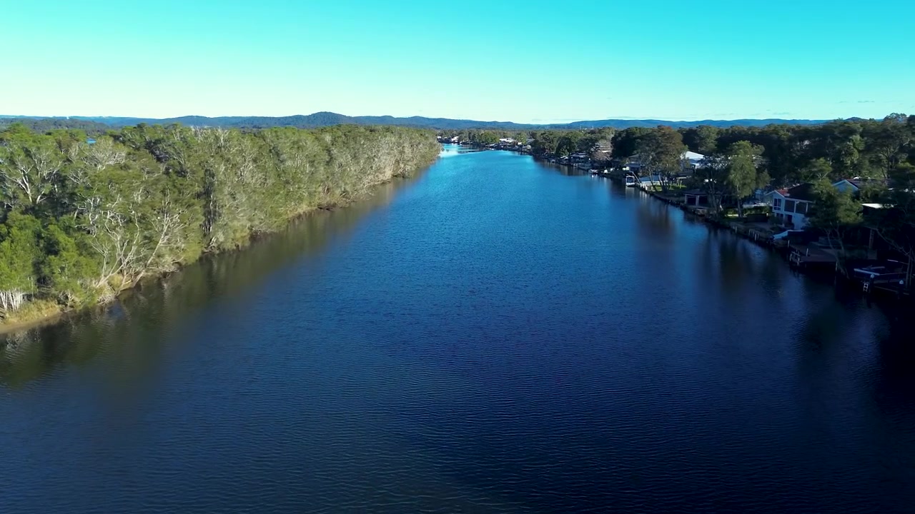 Dronekuva Ourimbah Creekin lahden vesipinnasta, jota ympäröivät pensaikkoiset metsäpuut ja asuinalueet niemimaalla Tuggerah-järven Chittaway Pointissa, Australian Keski-rannikolla.