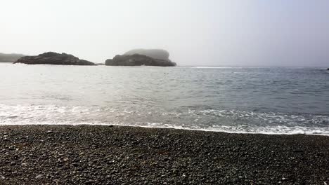 foggy ocean beach with dark pebbles