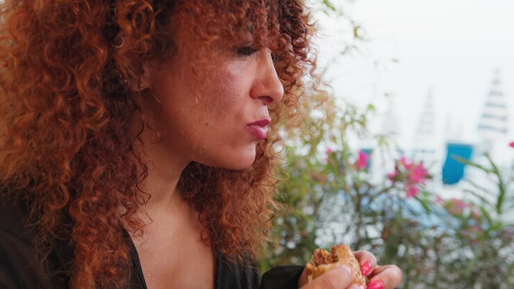 Woman Eating A Burger With Her Hands At The Beach Resort