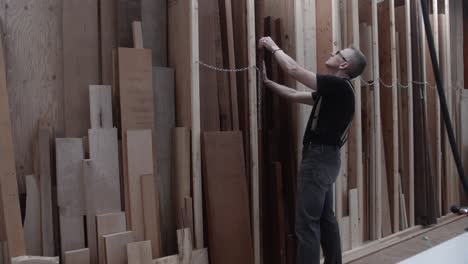 woodworker selecting rough lumber from storage rack in wood work shop