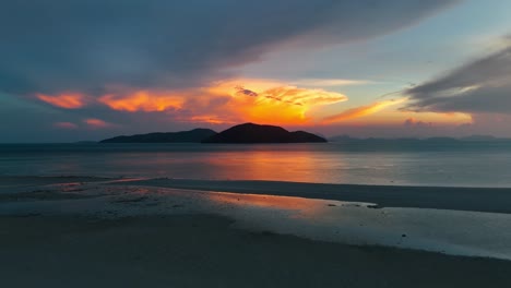 Dramatischer-Blick-Auf-Den-Sonnenuntergang-Von-Einem-Strand-Mit-Einer-Insel-In-Der-Ferne