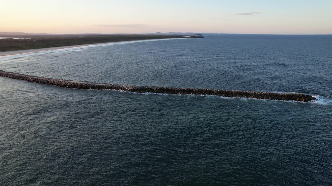 ponerse el sol sobre la playa de iluka y romper la pared en shoal bay en iluka, nsw, australia