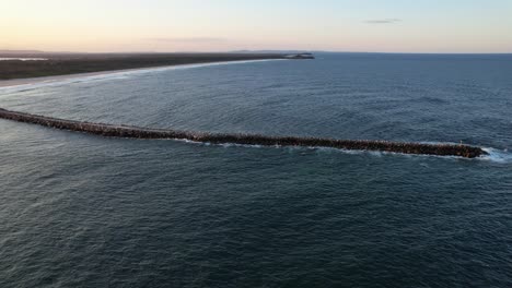 ponerse el sol sobre la playa de iluka y romper la pared en shoal bay en iluka, nsw, australia