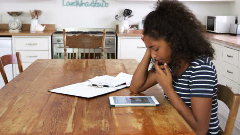 stressed teenage girl with digital tablet revising for exam