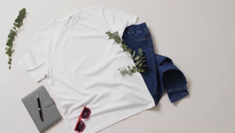 video of white t shirt, denim trousers, notebook, sunglasses and copy space on white background