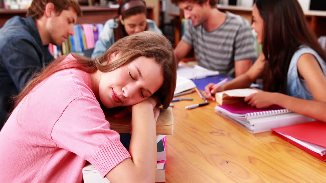 estudiantes estudiando juntos en la biblioteca con chicas durmiendo en libros
