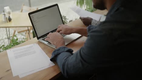 man typing on laptop computer in coffee shop