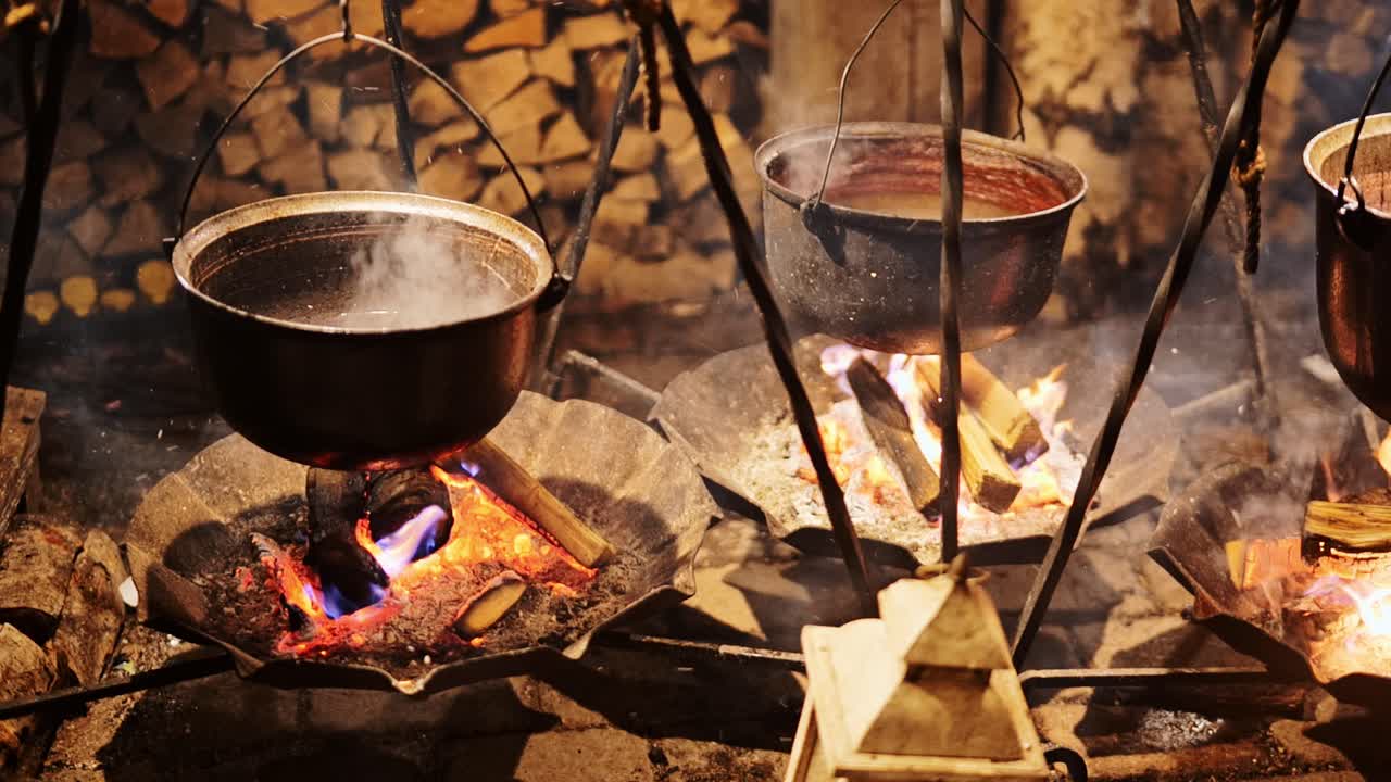 Close up boiling pots over open fire at night symbolizing heat energy and unity