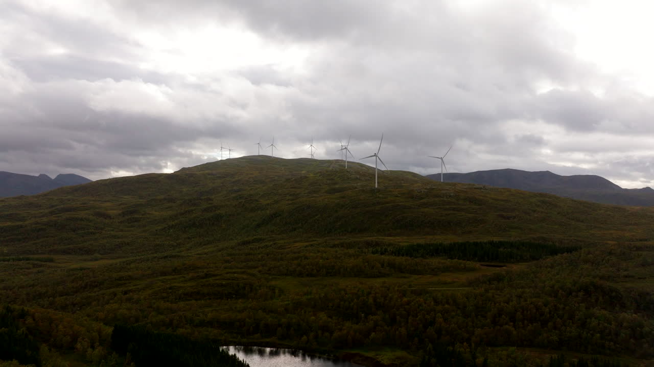 노르웨이 소르트랜드에서 구름이 가득한 하늘을 향해 산 위에서 회전하는 풍력 터빈.