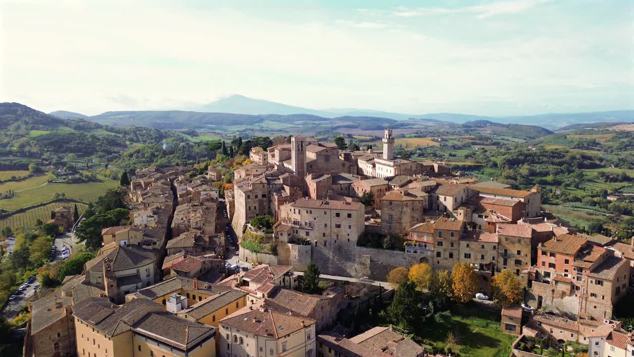 Aerial panorama of Tuscan town Montepulciano surrounded by vineyards under golden afternoon sunlight, approach