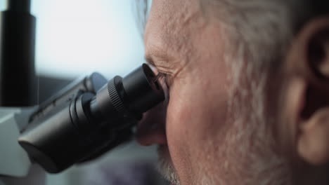 scientist looking through microscope