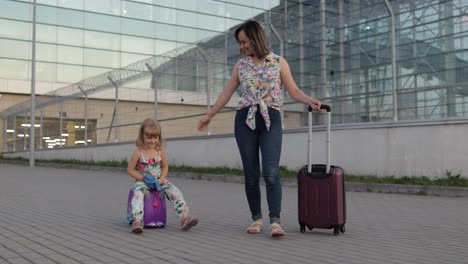 madre, hija caminando desde el aeropuerto después de las vacaciones. mujer llevando equipaje. niño viaja maleta