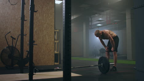 tired male athlete in the gym rests and prepares to perform an exercise. slow-motion sweaty athlete breathes heavily and concentrates on exercise