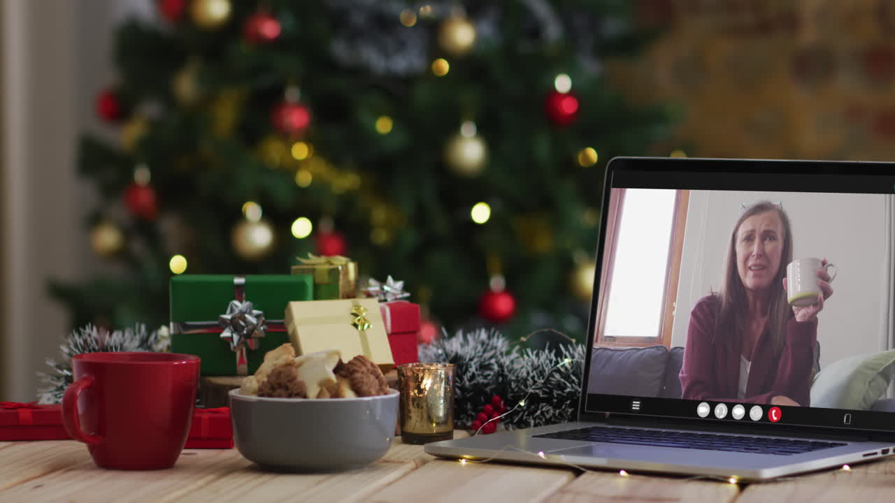 feliz mujer mayor caucásica en videollamada en computadora portátil, con decoraciones de navidad y árbol