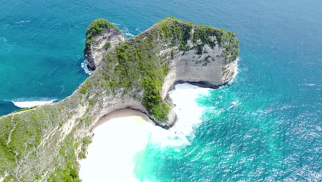 View-of-huge-green-cliff-standing-tall-along-the-ocean-coastline-on-a-bright-sunny-day