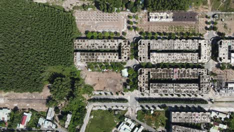 drone footage capturing the intricate layout of urban buildings in vietnam under bright daylight, showcasing the geometric symmetry and the blend of natural greenery with urban architecture