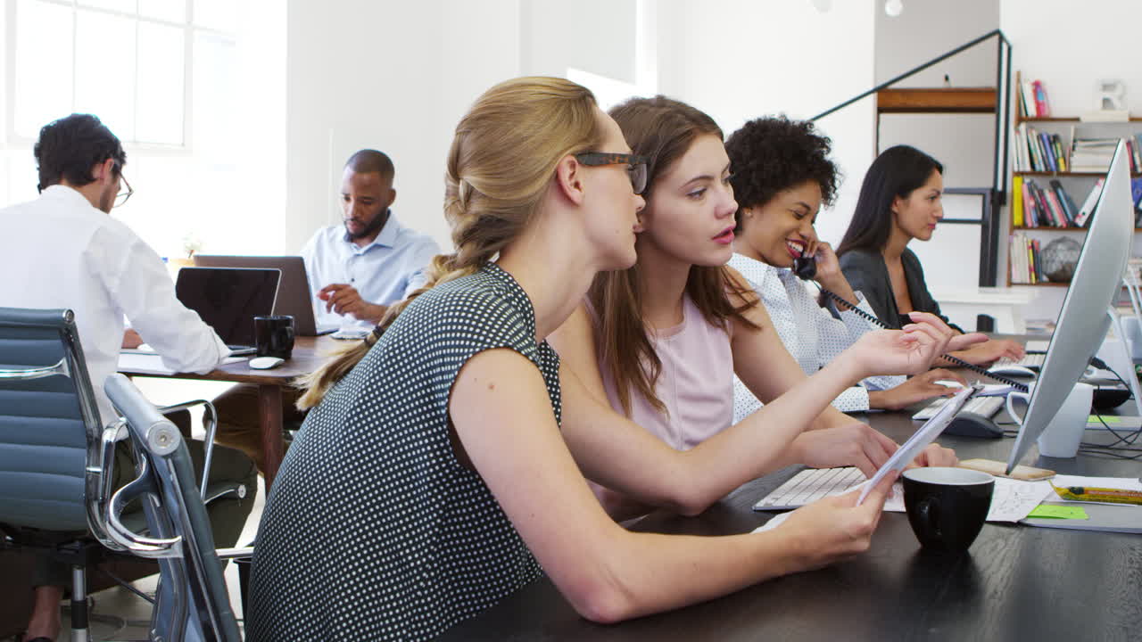 Woman training new female employee in an open plan office