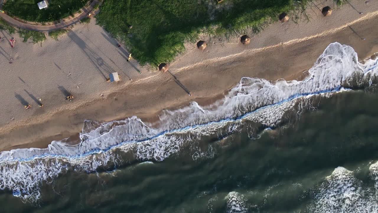 ojo de pájaro aéreo descendiendo sobre la playa con gente irreconocible caminando