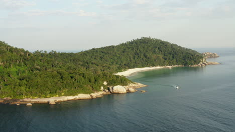 Aerial-view-of-a-motorboat-leaving-a-paradise-beach,-Campeche-Island,-Florianopolis,-Santa-Catarina,-Brazil
