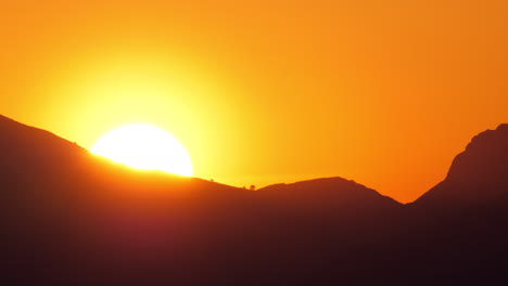 a sun setting behind the mountain cliff