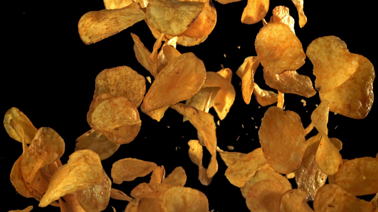 Golden Potato Chips Falling in Slow Motion on Black Background