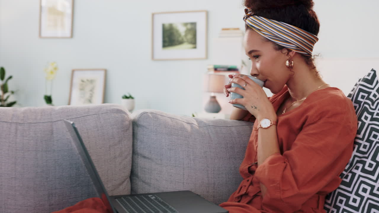 Kvinde slapper af på sofaen med bærbar computer og kaffe