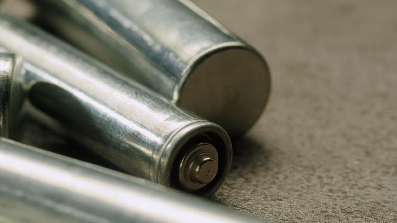 Silver batteries AA and AAA on black background close-up. Double-A battery is a standard size single cell cylindrical dry battery. Batteries are common in portable electronic devices. An AA battery is composed of a single electrochemical cell that may be either a primary battery or a rechargeable ba