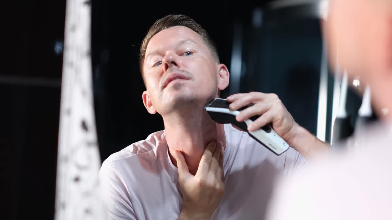 Man shaving his beard in the mirror