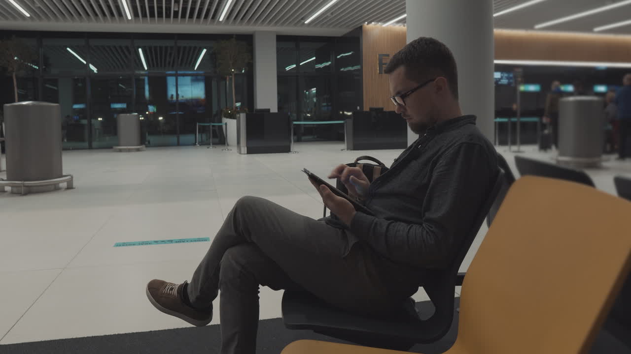 hombre usando tableta en la terminal del aeropuerto por la noche
