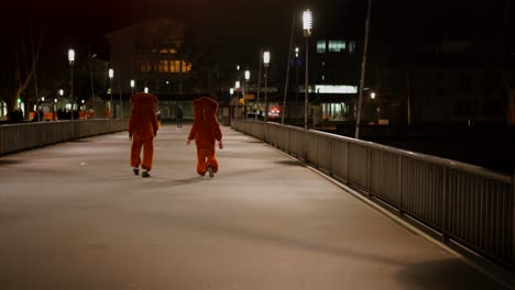 static rear shot of two drunken people in bear costume outfit going home after party at night