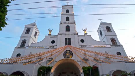 front view of the white facade of santo niño parish church in tacloban with hanging decorations and bell towers.