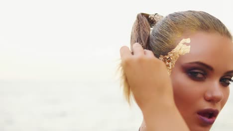 A-sexy-woman-with-professional-golden-makeup-looks-at-the-camera-and-flirts-with-the-viewer.-She-touches-her-hair.-Camera-moves