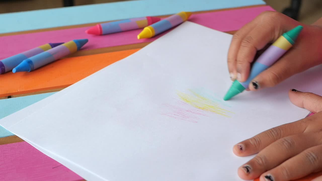 Child's Hands Drawing and Coloring on White Paper with Crayons