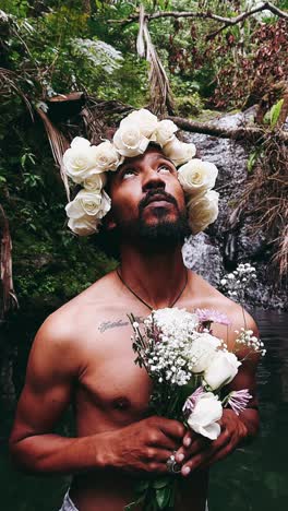 man with floral crown in a waterfall environment