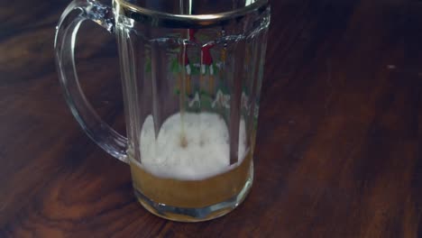 narrow focus closeup: refreshing beer is poured into large beer glass