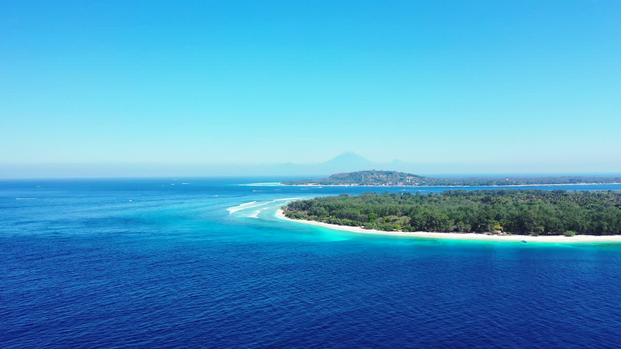 Speedboat tracing across beautiful blue sea coming from tropical island with white sandy beaches and trees forest in Bali