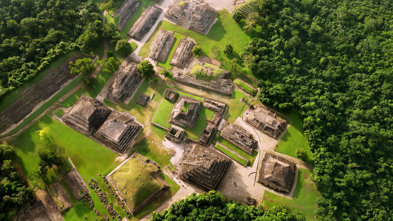 Aerial drone view of ancient Mayan ruins hidden within a dense green jungle