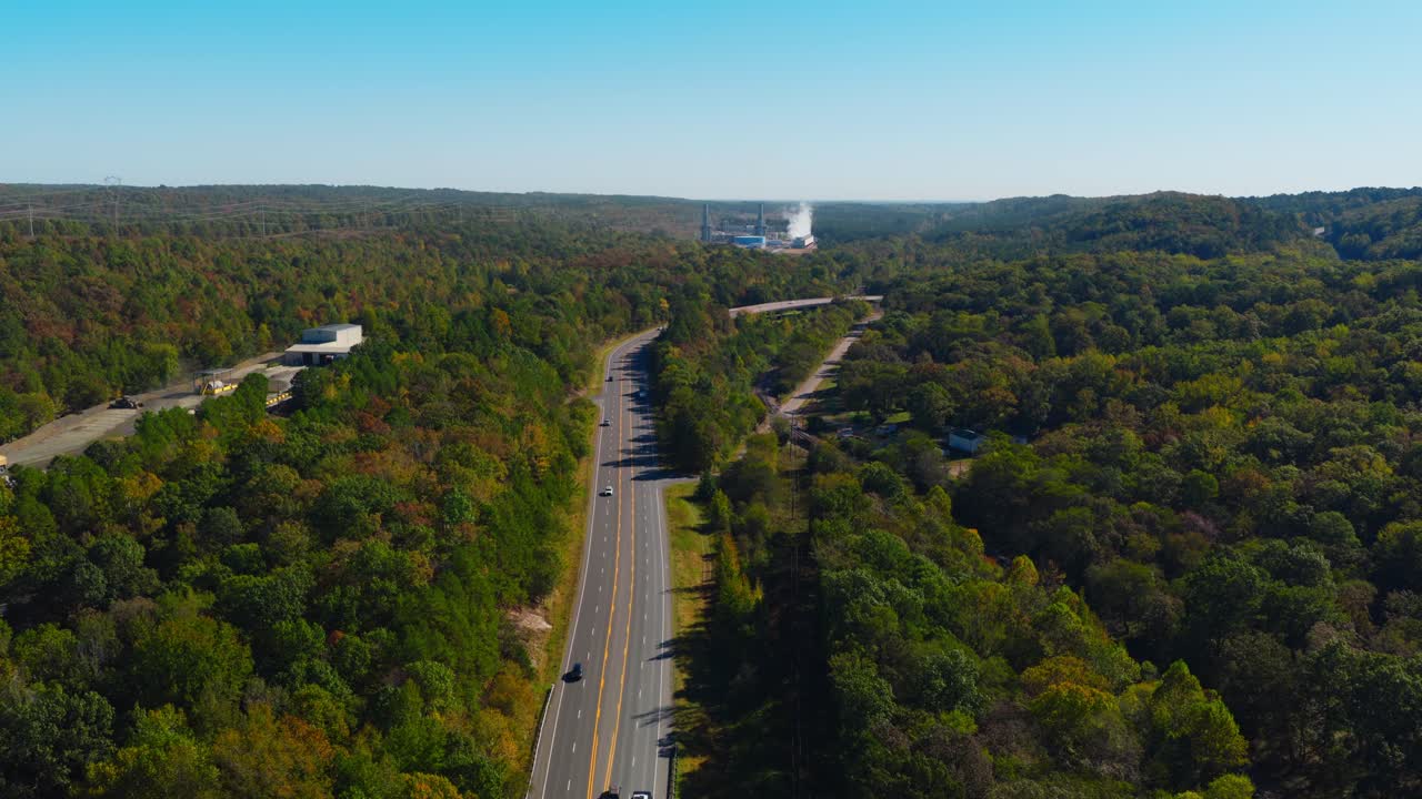 Rodovia rural através da floresta levando a um complexo industrial com vapor e fumaça subindo entre as árvores, Pedreira Jones Mill Arkansas EUA.