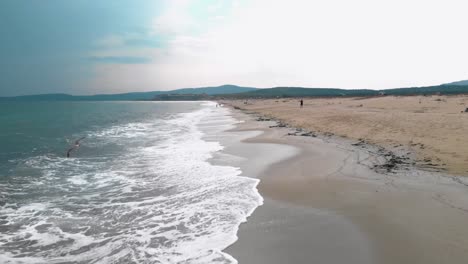 Drone-flying-straight-ahead-parallel-the-seashore-in-cloudy-day-with-seagulls-in-front---Sozopol,-Bulgaria