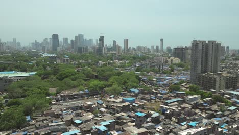 drone flyover dharavi slum rooftops with mumbai skyline in background, india