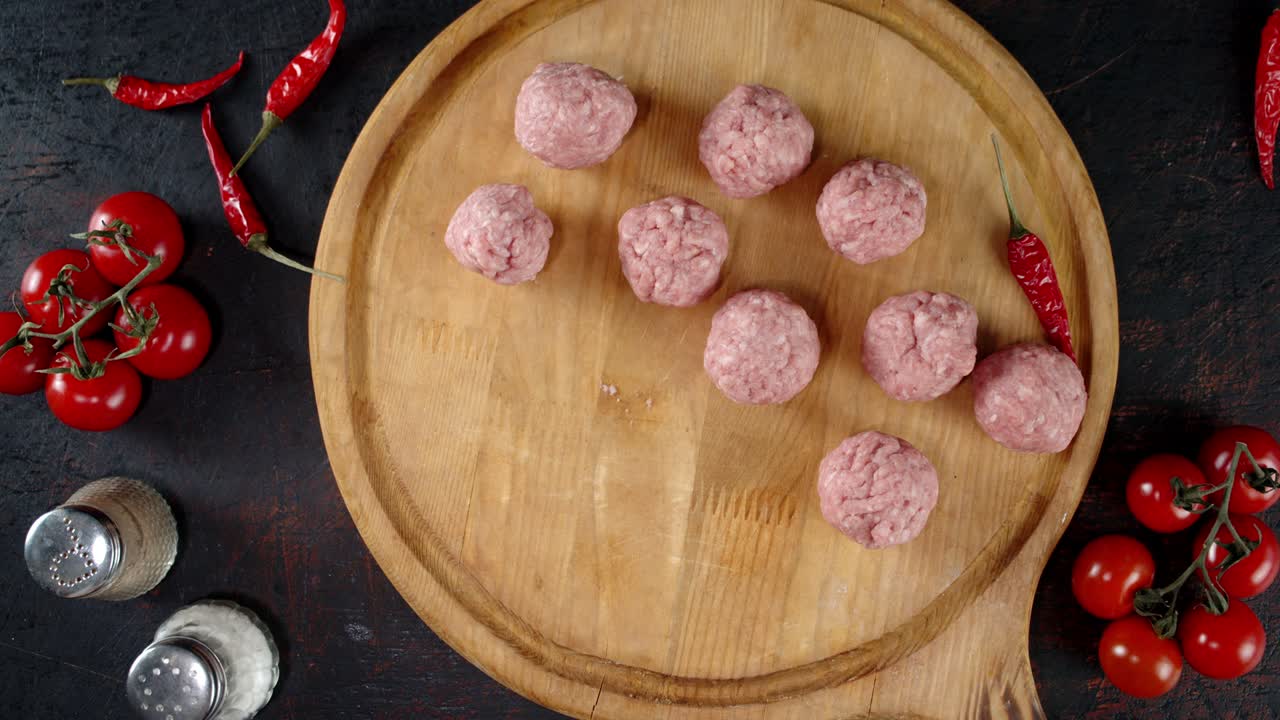 la mano masculina pone las albóndigas crudas en una tabla de cortar.