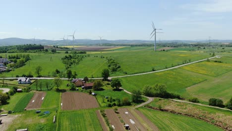 Wind-turbines-producing-clean-electric-power-on-green-fields,-farmland-infrastructure-aerial-view