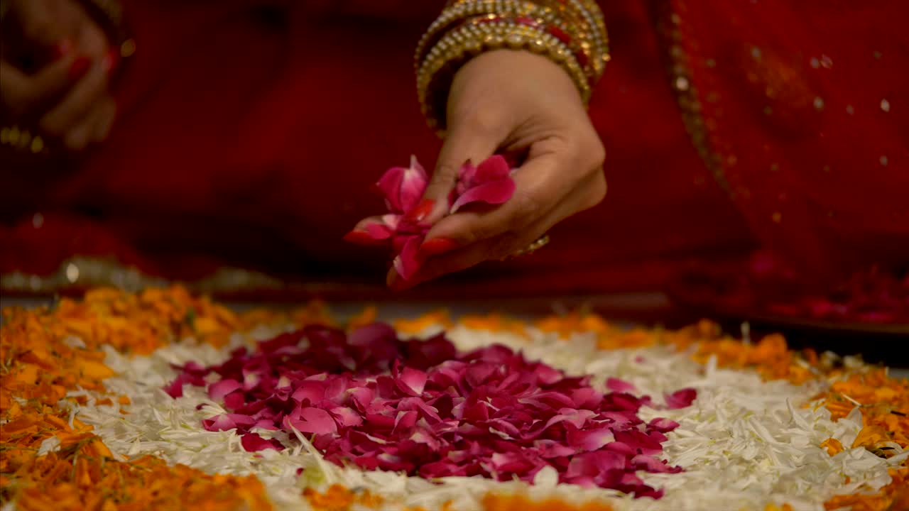 Diwali decoration - Indian women making flower rangoli with rose petals